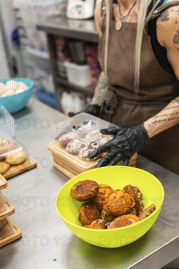 A baker at an Italian bakery prepares fresh pastries on a stainless steel countertop A vibrant green bowl holds an assorted variety, showcasing authentic culinary craftsmanship