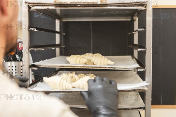 A baker places raw croissants onto a baking rack in an Italian bakery The scene captures the artisanal process and dedication in creating traditional pastries