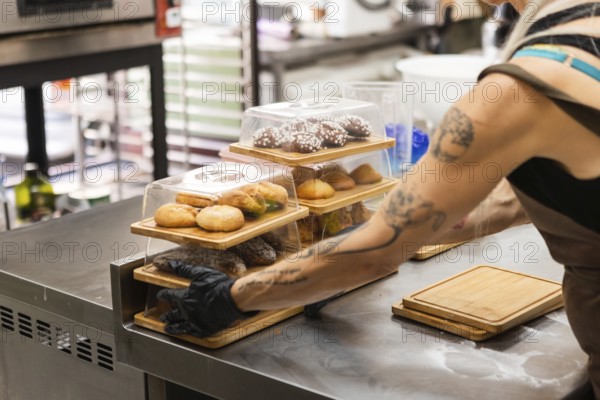 A baker prepares pastry boxes full of Italian delicacies Behind the counter, fresh pastries are neatly stacked, highlighting the charm of the Italian bakery
