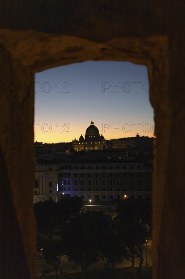 A stunning view of St Peter's Basilica framed by ancient architecture at twilight, with a vibrant orange and blue sky Perfect for themes of Roman beauty and history