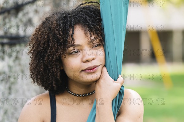 A black woman embraces silk fabric in a serene moment during a park acrobatics session in Bogota The lush greenery adds a fresh backdrop to this captivating aerial display
