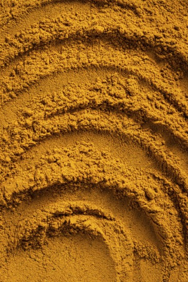 A vibrant close-up of golden curry powder, showcasing its textured surface with swirling patterns This aromatic spice is perfect as an ingredient for cauliflower curry soup and more