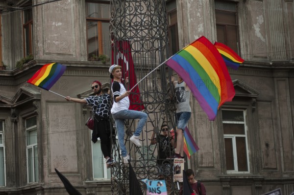Istanbul, Turkey. August 21st, 2016 Rainbow flag waiving protestors climb a statue near Istiklal Street, Istanbul during Gay Pride