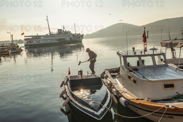 Istanbul, Turkey. 13th April 2016 Cleaning boat decks in the beautiful morning light on Burgazada Island as the Istanbul ferry leaves the port