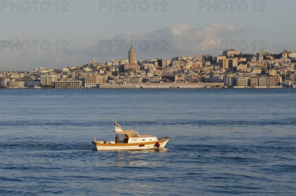 Istanbul, Turkey. August 19th 2014 A small fishing boat on the Bosporus straight with the Galata Tower and European Istanbul skyline, Turkey