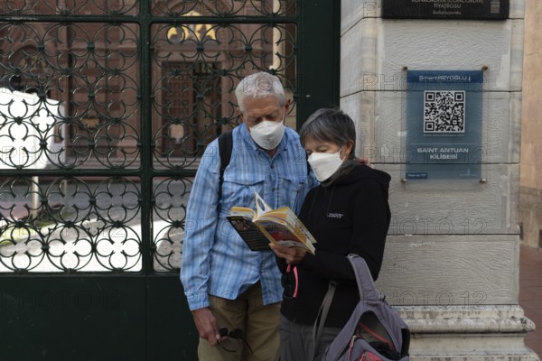 Istanbul, Turkey. October 5th 2021 Foreign tourists wearing protective masks reading a guide book outside St Antuan Church, Istiklal Street, Taksim, Istanbul