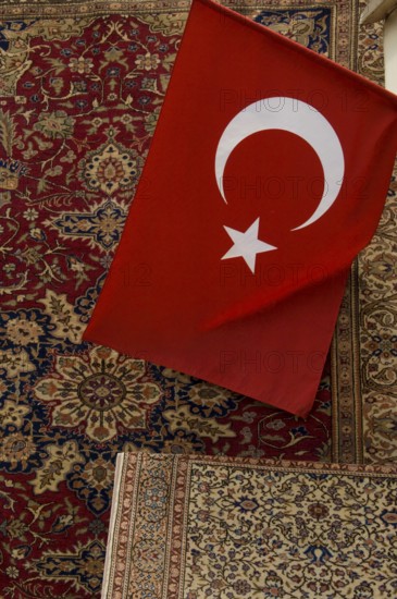 Istanbul, Turkey, February 23rd 2018. A Turkish flag and antique carpet for sale in a shop in the Grand Bazaar, Istanbul, Turkey