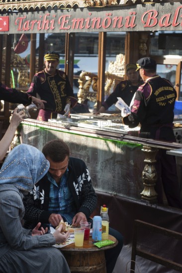 Istanbul, Turkey. April 12th 2016 A Turkish couple eating a fish sandwich the famous street food Balik Ekmek beside the Golden Horn, Istanbul, Turkey