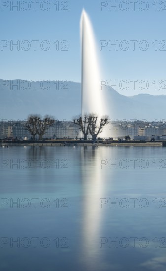 A tranquil shot of Geneva's iconic Jet d'Eau fountain, majestically rising above Lake Geneva against a backdrop of distant mountains