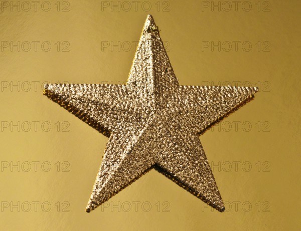A golden Christmas star shines with a glittery surface against a textured golden background, symbolizing festive cheer and decoration