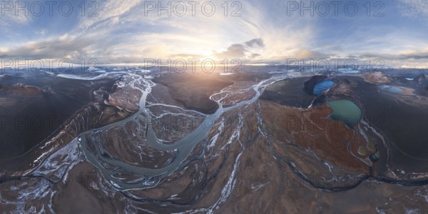 A breathtaking aerial view of Iceland's Highlands at sunrise, showcasing meandering rivers, volcanic landscapes, and glacial vistas under a vast, dramatic sky