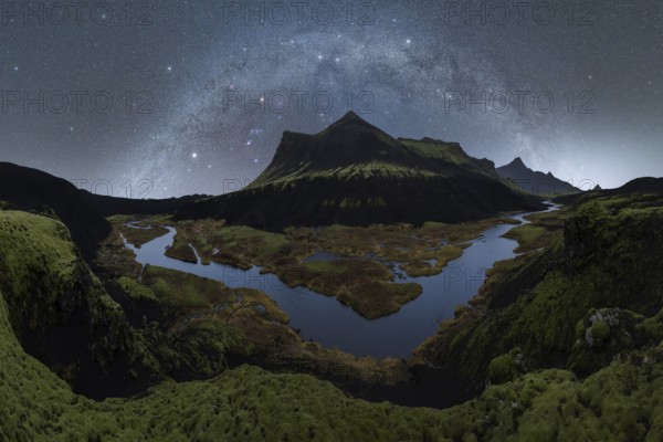 Experience the mesmerizing beauty of Iceland's night sky, where the Milky Way arches over serene mountains and winding rivers, offering a breathtaking view of nature's wonder