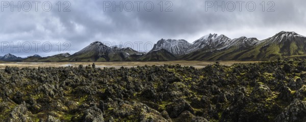 A breathtaking panoramic view of Iceland's rugged Highlands, showcasing jagged peaks, moss-covered lava fields, and a dramatic sky The pristine wilderness captivates with its raw beauty