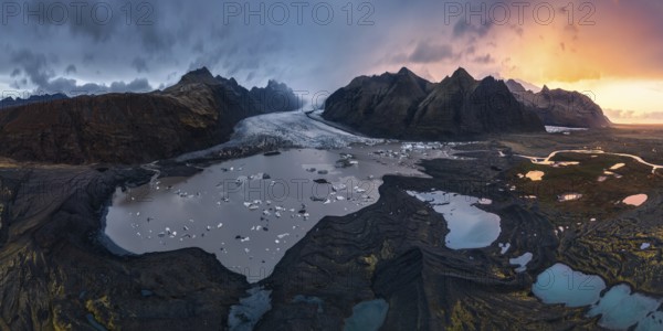 Panoramic view of Vatnajokull National Park at sunset, showcasing majestic glaciers, rugged mountains, and serene waters in a stunning Icelandic landscape