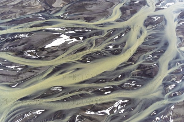 Stunning aerial capture of Iceland's golden rivers, gracefully weaving through patches of snow, showcasing the unique and breathtaking landscapes of the region