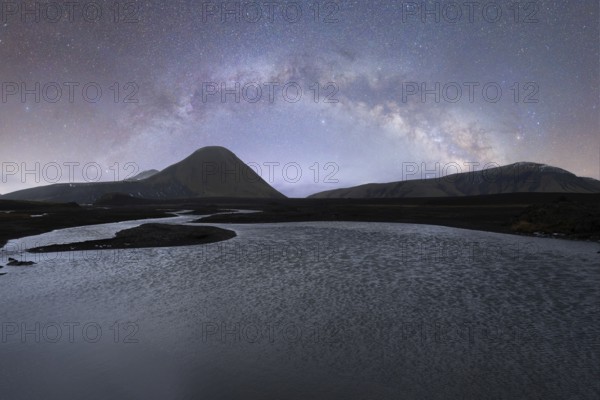 A breathtaking view of the Milky Way arching over a serene Icelandic landscape The clear, starlit sky illuminates the tranquil river and rugged mountains