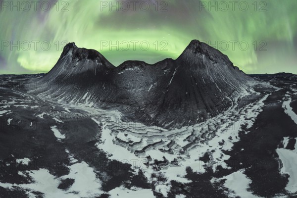 Awe-inspiring aurora borealis dances in the night sky above snow-dusted mountains and rugged terrain in the wilds of Iceland