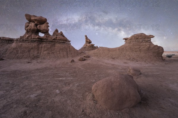 Under the vast night sky, unique sandstone formations of Goblin Valley State Park, Utah, create a surreal landscape. The Milky Way enhances the ethereal beauty of the desert night