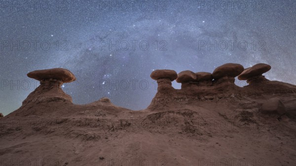 Goblin Valley State Park in Utah, USA, under a breathtaking Milky Way. The desert landscape showcases distinctive rock shapes against a star-filled sky