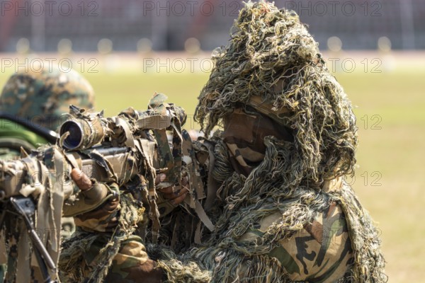 A camouflaged sniper of the Central Reserve Police Force takes aim during a tactical demonstration at the 87th Raising Day celebrations, on February 19, 2026 in Guwahati, India