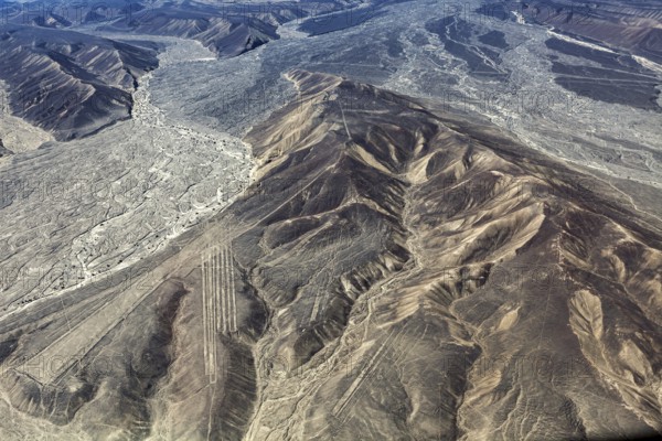 Aerial view shows mountainous desert landscape with clear geoglyph lines, the geoglyphs and images in the desert near Nasca and Palpa in Peru