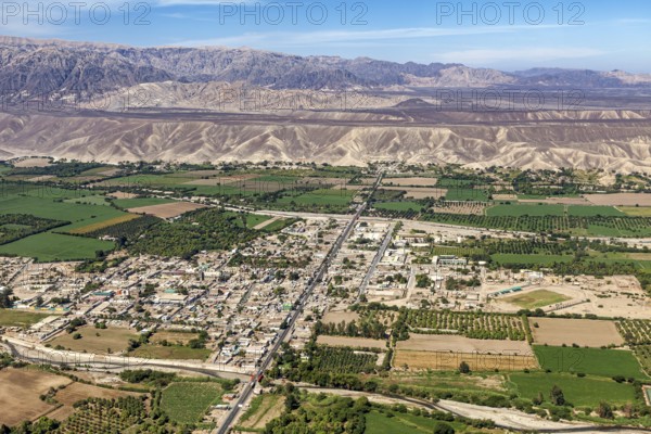 Expansive aerial view of a city with green fields and mountains in the background, The city of Nasca in Peru