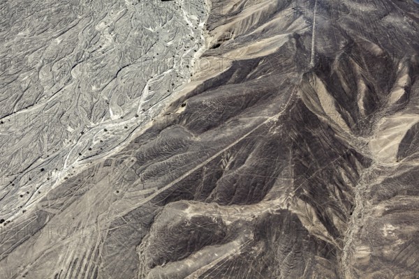 Aerial view of a desert with distinctive hills and line patterns, the geoglyphs and images in the desert near Nasca and Palpa in Peru