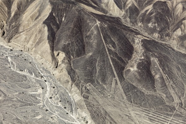 A mountainous country with a recognizable line pattern flying over the desert, the geoglyphs and images in the desert near Nasca and Palpa in Peru