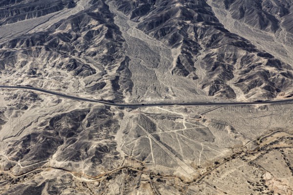 Barren landscape with visible geoglyphs and a straight road, the geoglyphs and images in the desert near Nasca and Palpa in Peru