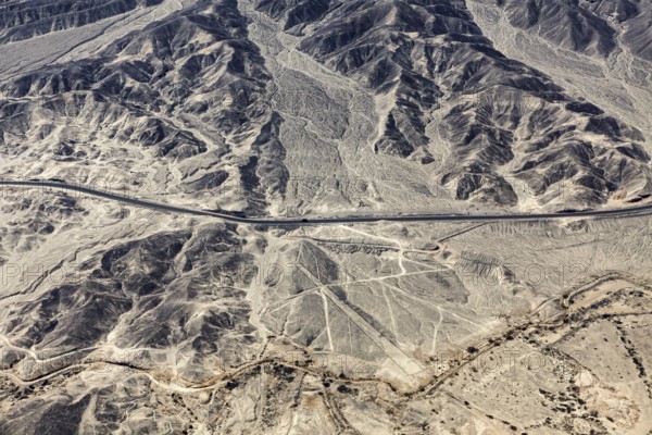 Dry, rocky desert landscape with lines and a highway, the geoglyphs and images in the desert near Nasca and Palpa in Peru