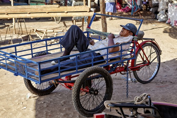 A man resting on a cart in a sunny market environment, The market in the streets of Nasca in Peru