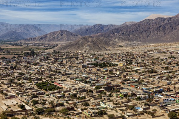 A panoramic view of a city against a backdrop of mountains and clear skies, the city of Nasca in Peru