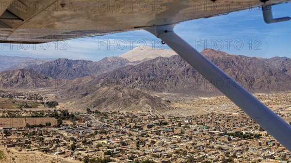 Aerial view of a city surrounded by mountains, viewed from the window of an airplane in clear skies, The city of Nasca in Peru