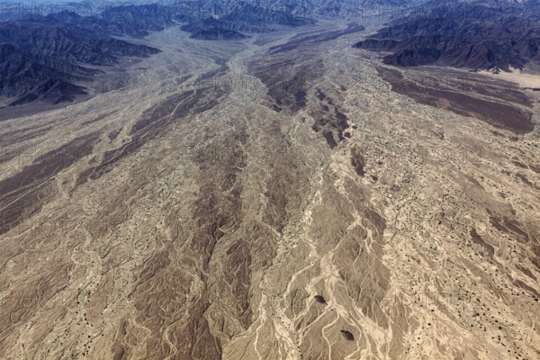 Impressive aerial view of a desert landscape with many earthy textures and furrows, central focus on the dry riverbed, the desert landscape near Nasca in Peru