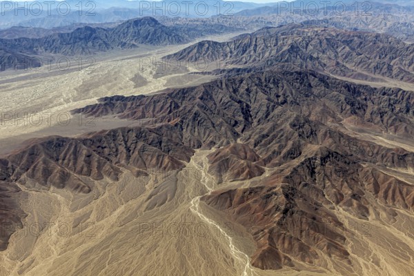Winding hills and a dry riverbed in an impressive, dry landscape with shades of brown colors, The desert landscape near Nasca in Peru