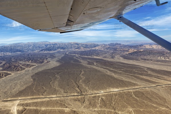 View from an airplane of a dry desert landscape with mountains and blue sky, The desert landscape near Nasca in Peru