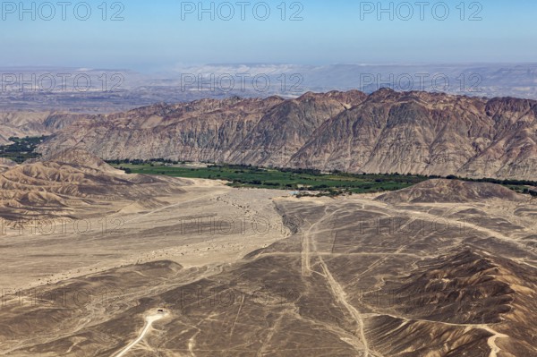 Dramatic desert plain with tracks and mountain panorama under clear sky, the desert landscape near Nasca in Peru