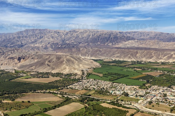 Diverse landscape with green fields and cityscape in front of a mountain panorama, The desert landscape near Nasca in Peru