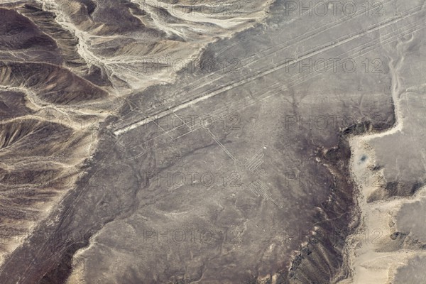 Geoglyphs in a vast sandy desert landscape with mountains, seen from the air, The geoglyphs and images in the desert near Nasca and Palpa in Peru