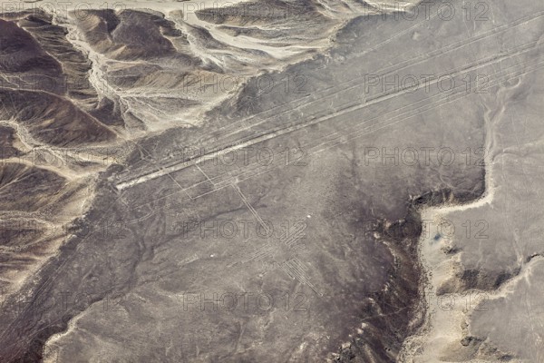 Lines and geoglyphs over an infinite desert plain, taken from lofty heights, with mountain slopes, the geoglyphs and images in the desert near Nasca and Palpa in Peru