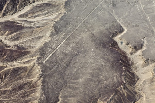 Desert area with linear geoglyph patterns, captured from the air, with mountains in the background, the geoglyphs and images in the desert near Nasca and Palpa in Peru