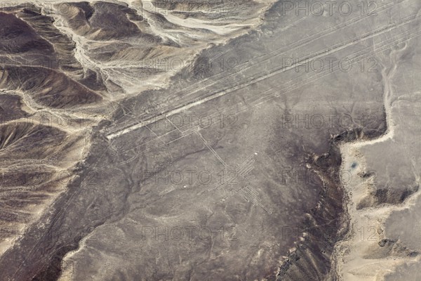 Lines and geoglyphs visible from the air in a desert-like environment surrounded by mountains, The geoglyphs and images in the desert near Nasca and Palpa in Peru