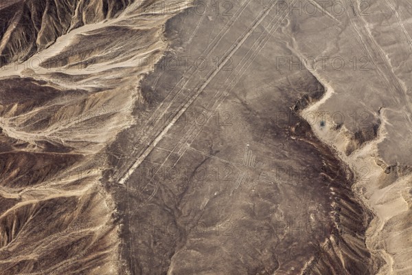 Desert landscape with recognizable lines and geoglyphs from the air, mountains surround the scene, the geoglyphs and images in the desert near Nasca and Palpa in Peru