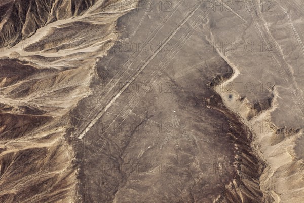 Sand-colored desert landscape with visible geoglyphs and linear patterns, surrounded by mountains, The geoglyphs and images in the desert near Nasca and Palpa in Peru