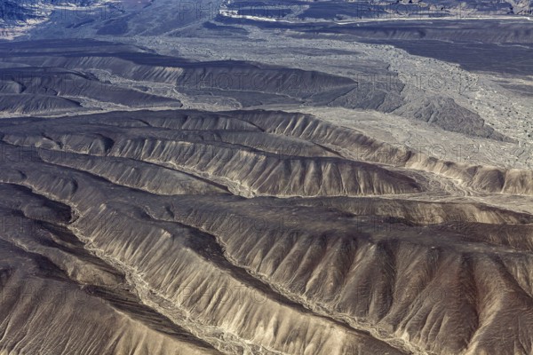 Aerial view of dry, folded mountains in a desert-like landscape, the desert landscape near Nasca in Peru