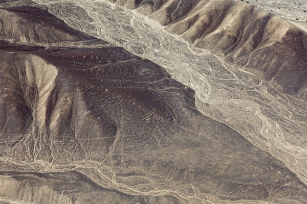 Aerial view of a desert with hills and ancient line formations, the geoglyphs and images in the desert near Nasca and Palpa in Peru