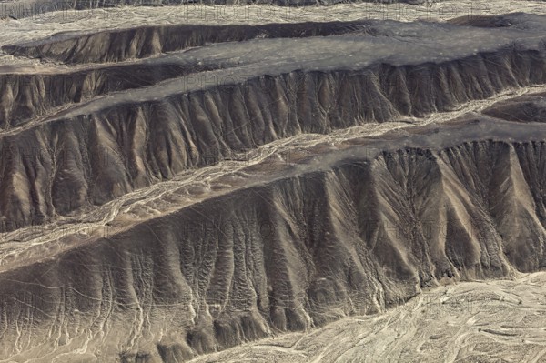 Aerial view of eroded hills in a desert landscape with brown earth tones, The desert landscape near Nasca in Peru