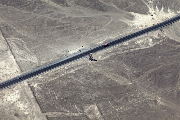 Aerial view of a dry environment with Nazca lines and a parallel road, The geoglyphs and images in the desert near Nasca and Palpa in Peru