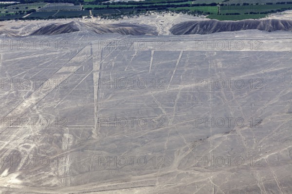 View of the desert with visible geoglyphs, fields and mountains lying in the distance, the geoglyphs and images in the desert near Nasca and Palpa in Peru