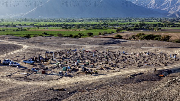 Rural cemetery in dry surroundings with green fields and mountain scenery in the background, cemetery in the Nazca desert in Peru